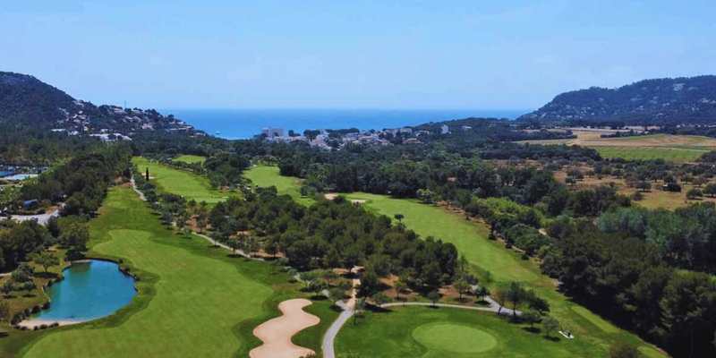 Vue aérienne d’un parcours de golf entre pins et Méditerranée à Majorque