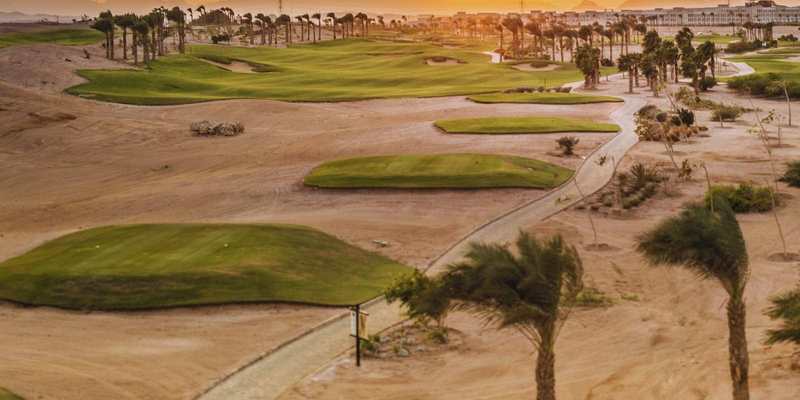 Parcours de golf et palmiers dans le désert au coucher du soleil en Égypte