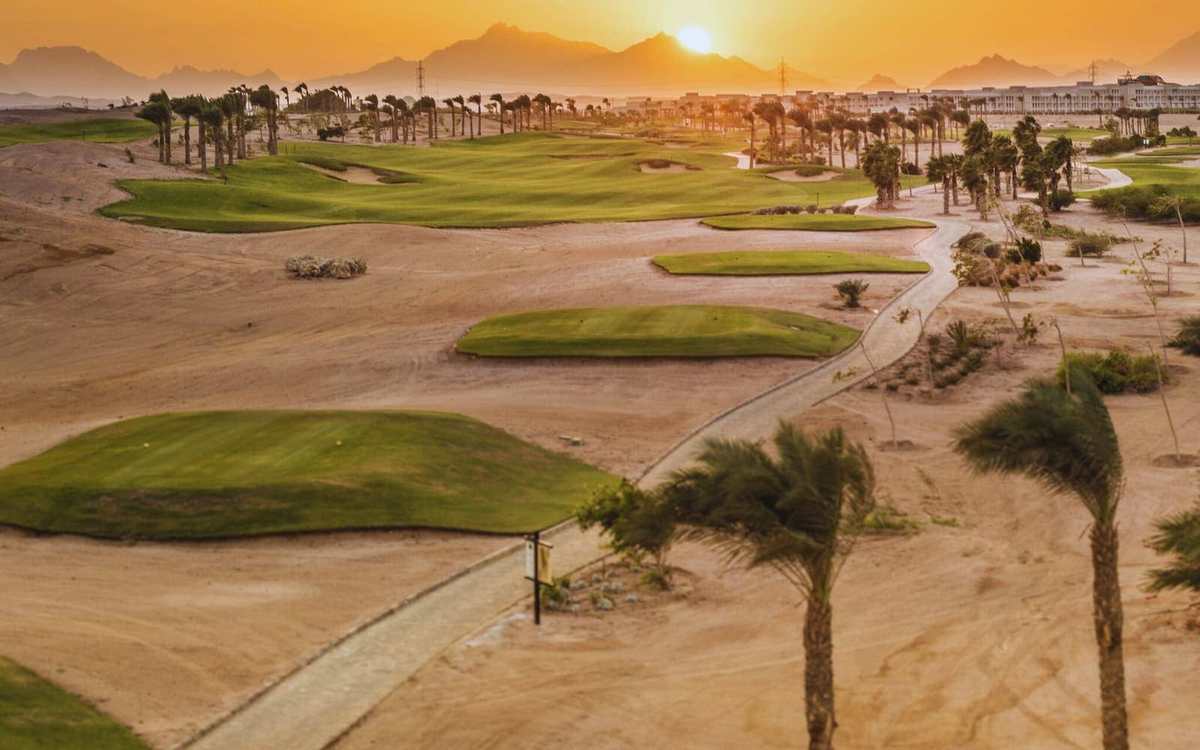 Parcours de golf et palmiers dans le désert au coucher du soleil en Égypte