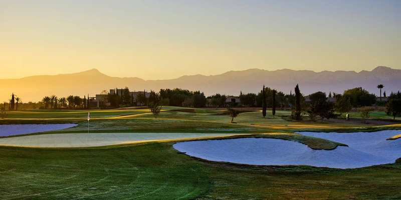 Parcours de golf et lac au lever du soleil devant l’Atlas, à Marrakech