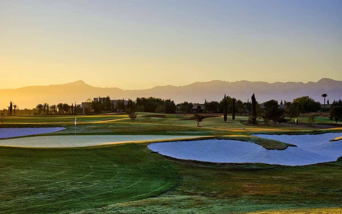 Parcours de golf et lac au lever du soleil devant l’Atlas, à Marrakech