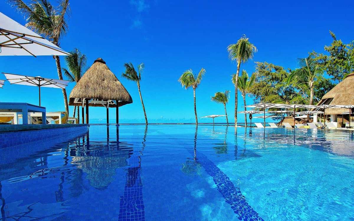 Piscine à débordement et paillotes face au lagon à l’île Maurice
