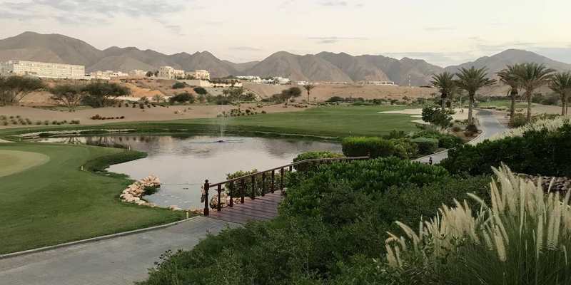 Parcours de golf et lac face aux montagnes près de Mascate
