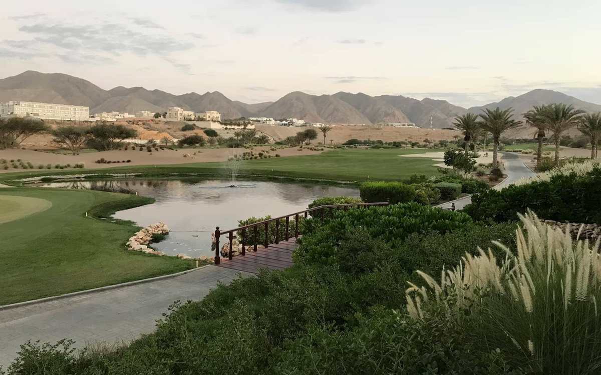 Parcours de golf et lac face aux montagnes près de Mascate